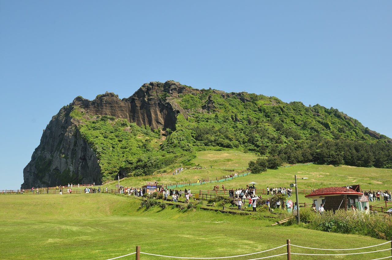 about-03 Scenic view of Seongsan Ilchulbong Peak in Jeju, South Korea with tourists enjoying the landscape.